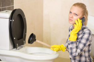 woman calling plumber by toilet