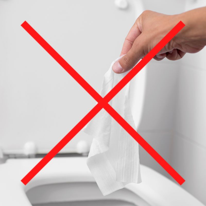 someone hold a wipe over an open toilet with a red "X" over the whole picture